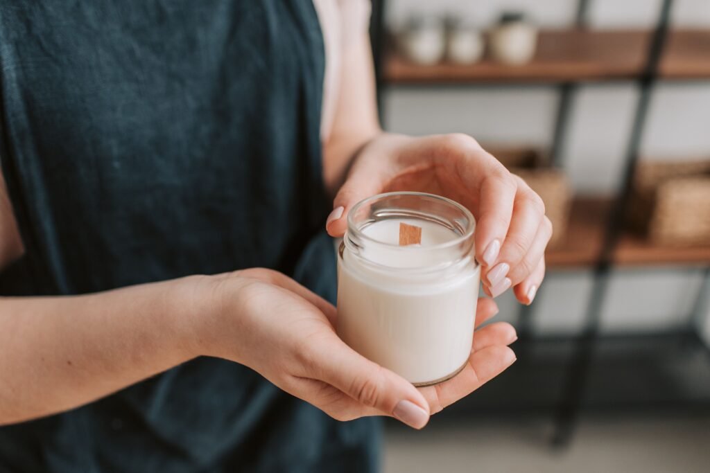 Soy candle in a glass jar on a wooden table as a Christmas gift.