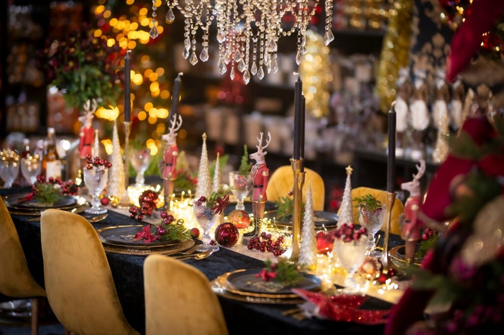 Elegant Christmas dinner table with black candles, gold candle holders, reindeer figures and warm fairy lights