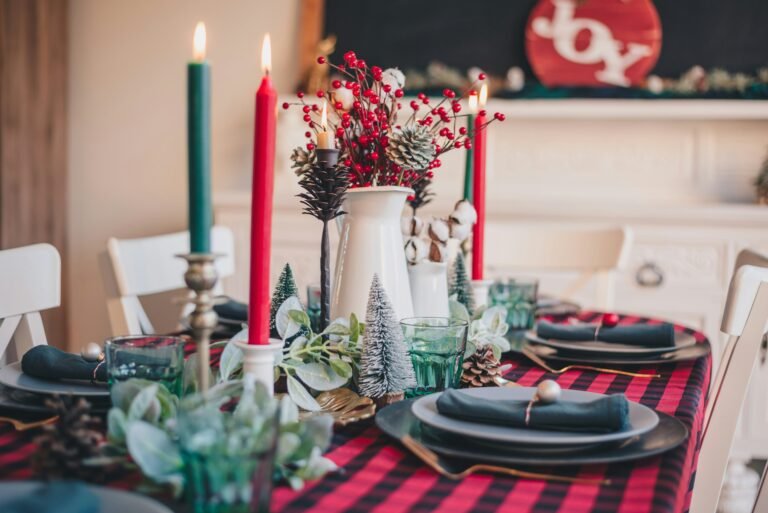 Christmas table decor ideas with a red plaid tablecloth, candles, greenery and mini trees on a holiday dinner table