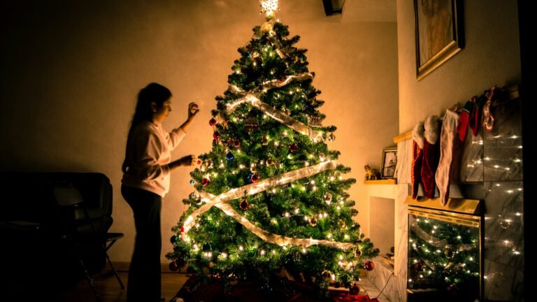 Christmas tree decorating ideas shown on a tree with warm white lights, ribbon and ornaments