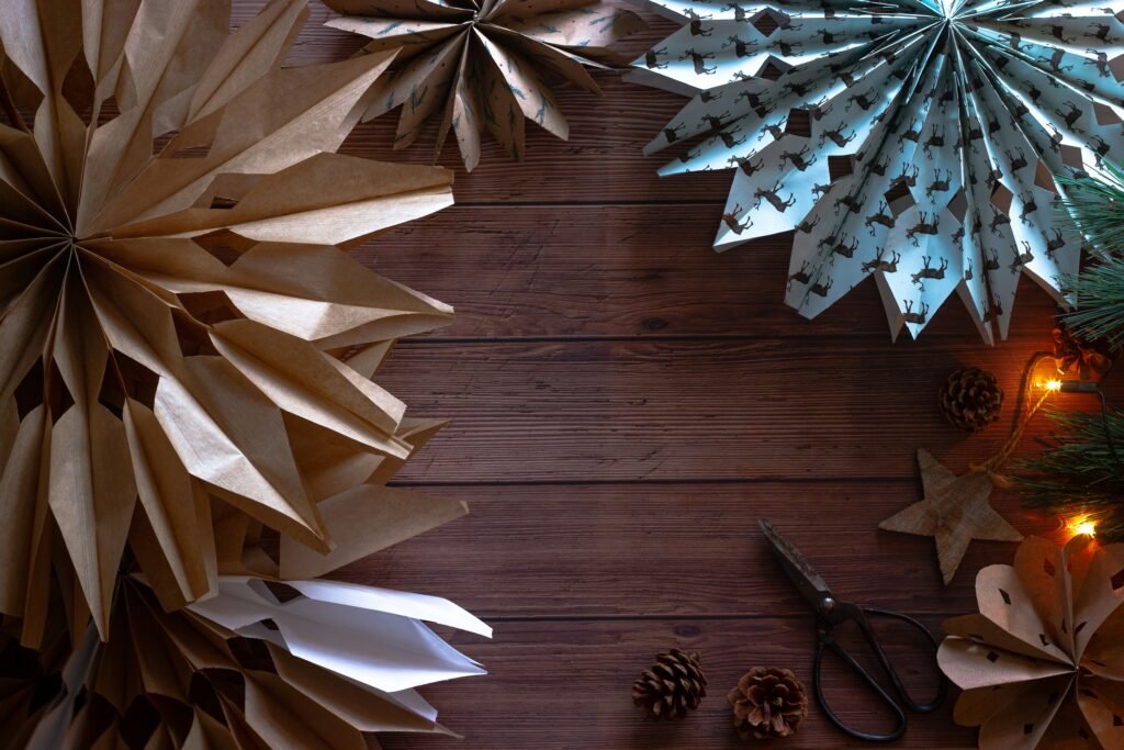 Handmade kraft paper stars with pinecones, scissors and warm lights on a wooden table, an easy DIY Christmas decor idea
